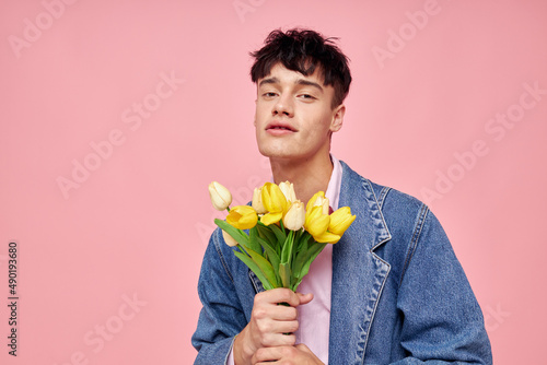 portrait of a young man bouquet of yellow flowers gift holiday elegant style pink background unaltered