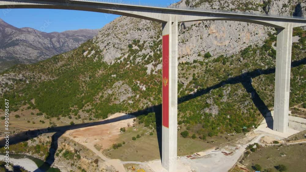 Aerial shot of the fully finished Moracica bridge in Montenegro. The big red coat of arms of Montenegro is seen on one of the bridge's pillar Aerial shot of the fully finished Moracica bridge in Montenegro. The big red coat of arms of Montenegro is seen on one of the bridge's pillar