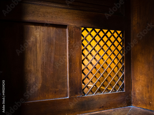 Closeup of a wooden window of the confessional box at church