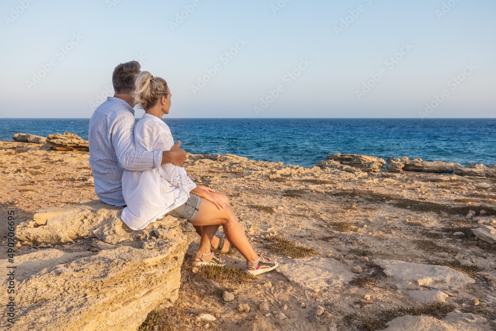 Loving mature couple enjoying their life together on the beach. Honeymoon lovers. Man and woman enjoying stunning sunset.