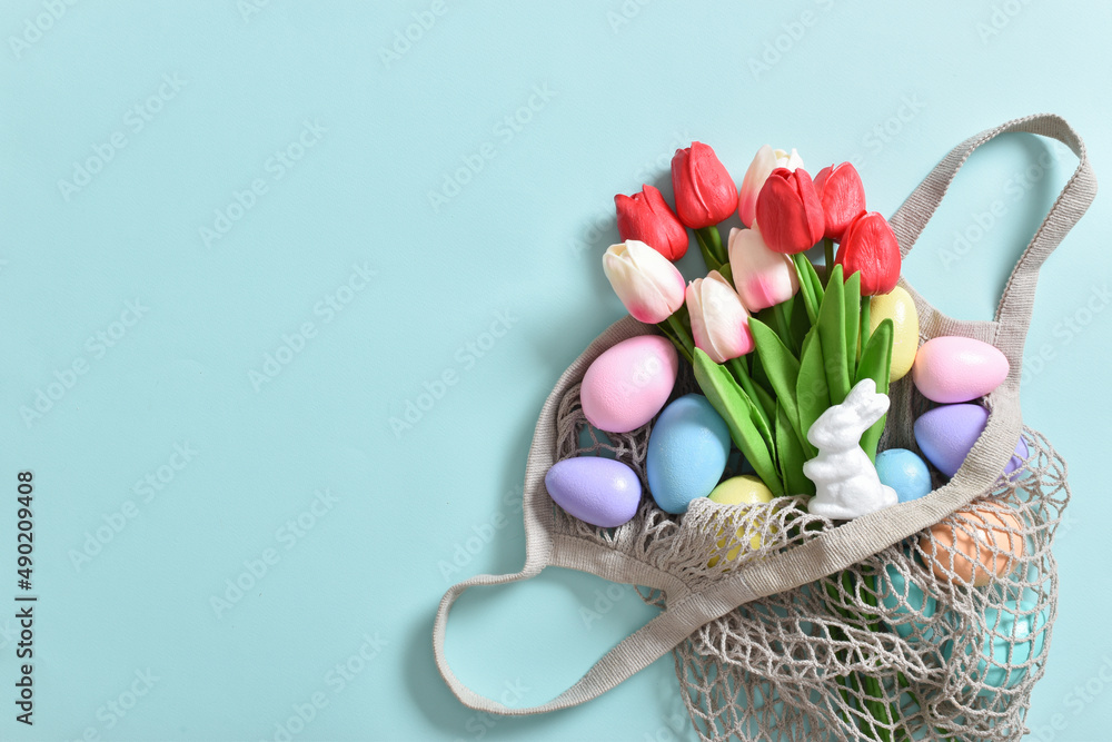 Obraz premium A beautiful bouquet of tulips with a string bag containing painted eggs.