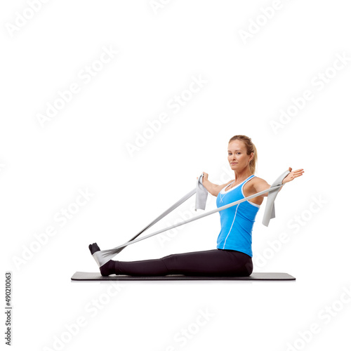Feeling that pull.... A young blonde woman sitting on a mat and exercising with a resistance band - portrait.