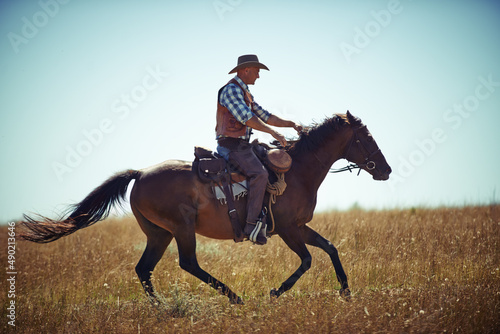 Ride em cowboy. Shot of a man riding a horse in a field.