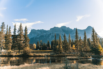 Beautiful wallpaper of a lake surrounded by fir trees and high snowy mountains in the background