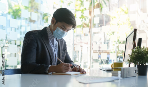 Asian businessman wearing protective mask working in modern office.