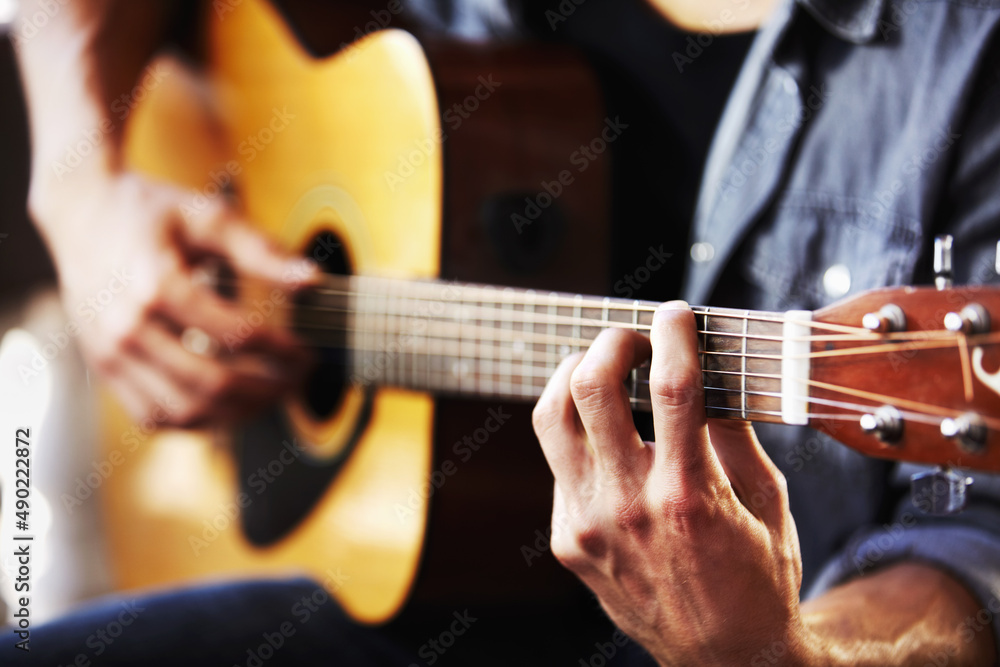His skill has been gained through hours of practice. Cropped view of masculine hands strumming a guitar.