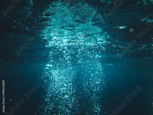 Underwater shot of sun rays going through deep ocean making water bubbles © Francesco Ungaro/Wirestock