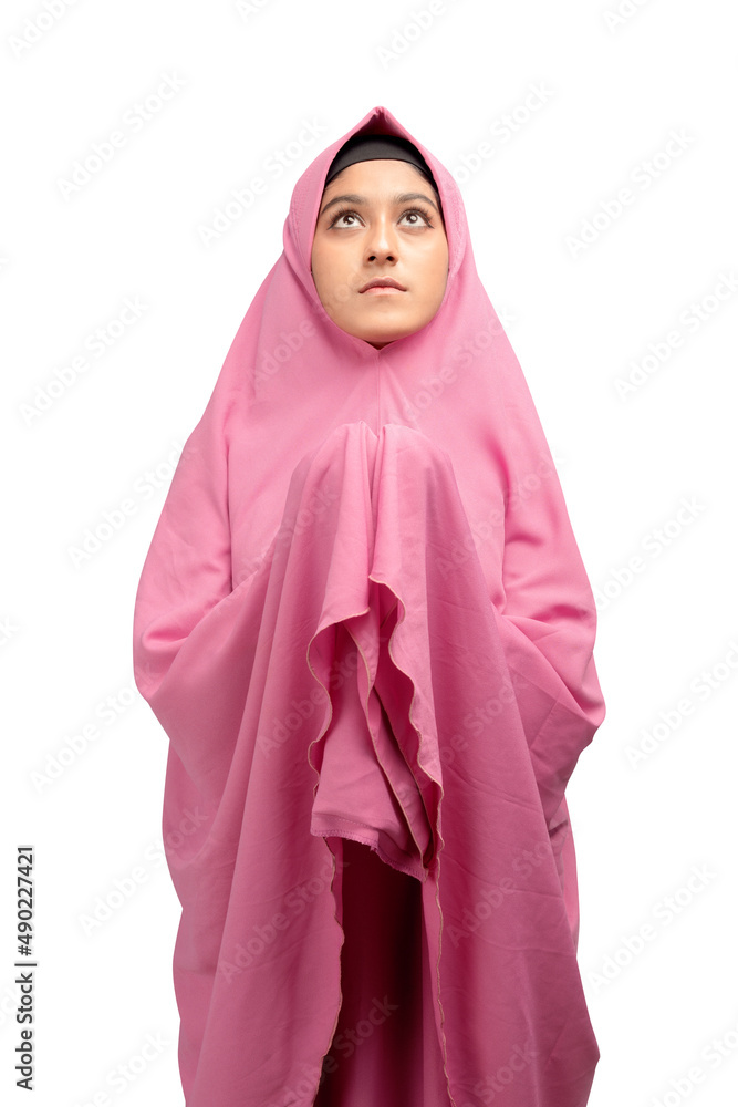 Asian Muslim woman in a veil standing while raised hands and praying Asian Muslim woman in a veil standing while raised hands and praying