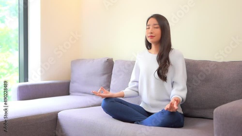 A lovely young woman sitting cross-legged strikes a yoga pose as she meditates. Title space photo