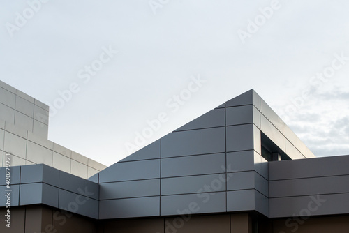 The exterior wall of a contemporary commercial style building with aluminum metal composite panels and glass windows. The futuristic building has engineered diagonal cladding steel frame panels. photo