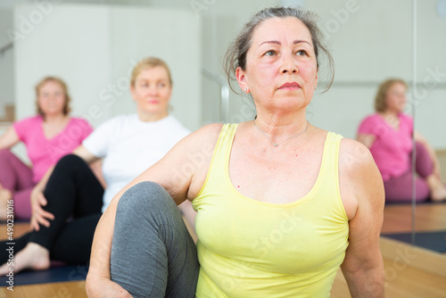 Women exercising during yoga class in modern fitness center - marichiasana pose
