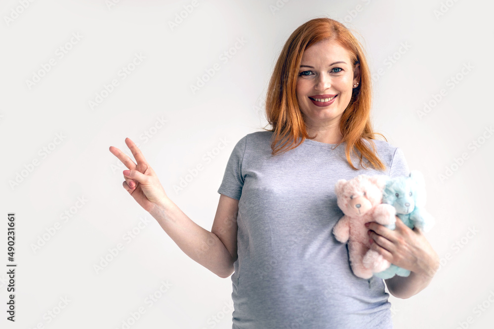 Obraz premium Closeup young pregnant woman hugging two bear toys on huge belly posing isolated on white studio