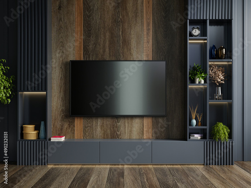Wooden wall mounted tv in modern living room with decoration on dark wall background.