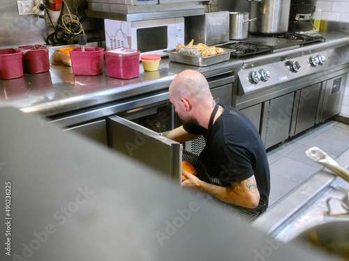 Cook storing food in stainless steel kitchen fridges