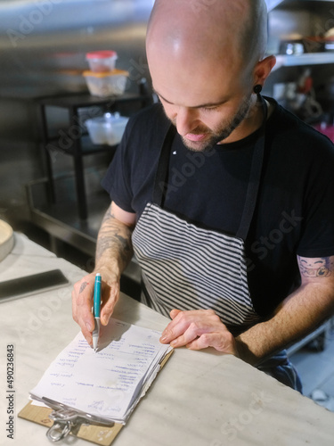 Cook checking the list of tasks to prepare the tasting menu in a restaurant