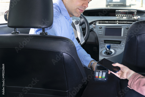 Fototapeta Passenger paying the taxi driver via POS machine with her phone