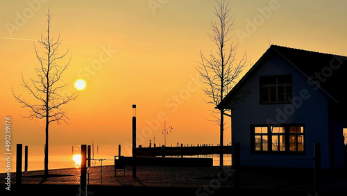 Scenic evening view of a small building next to a body of water against an orange sky photo