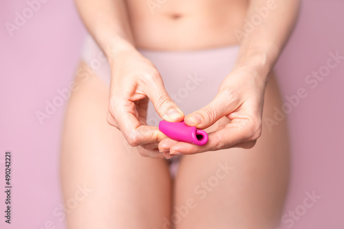 A young woman folding a pink menstrual cup in her hand. Pink colored background. Space for text. Eco-friendly silicone women's health cycle © Анна Брусницына