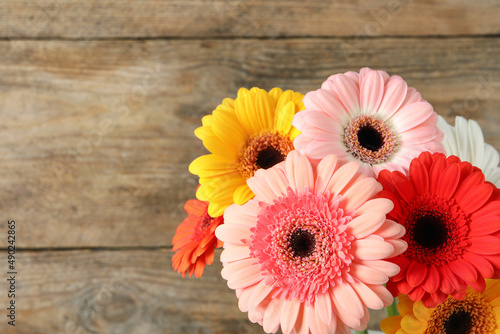 Bouquet of beautiful colorful gerbera flowers on wooden background. Space for text