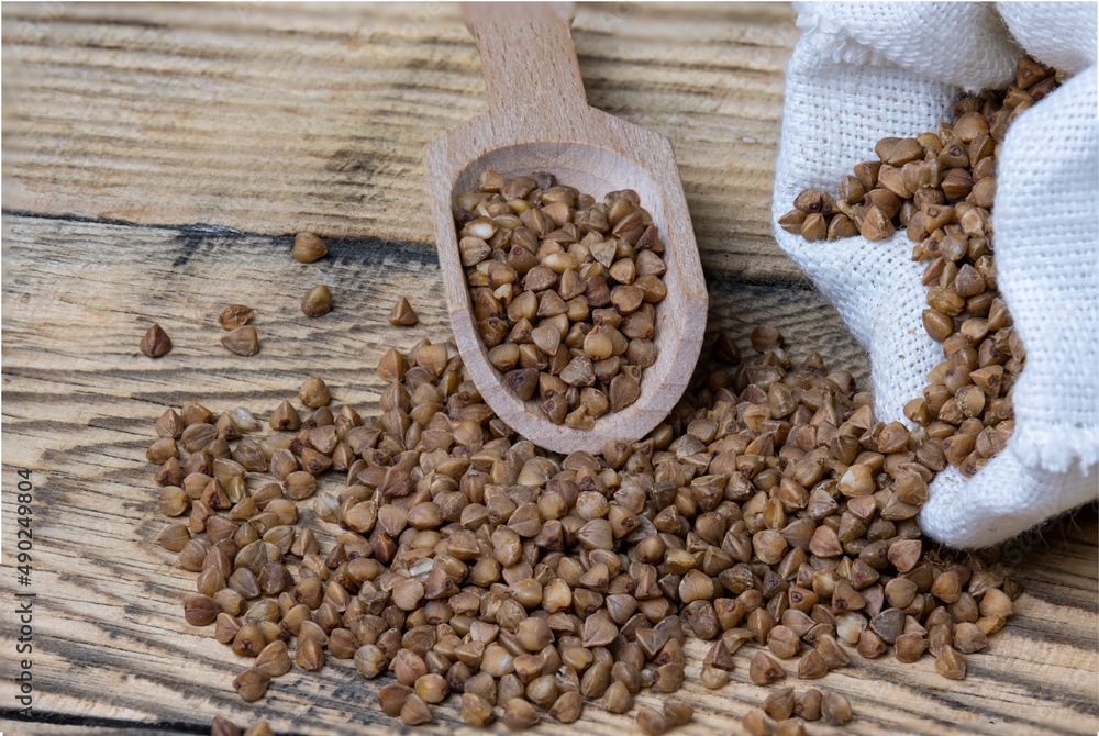 Buckwheat in a wooden spoon and in a canvas bag on the table. Buckwheat in a wooden spoon and in a canvas bag on the table.