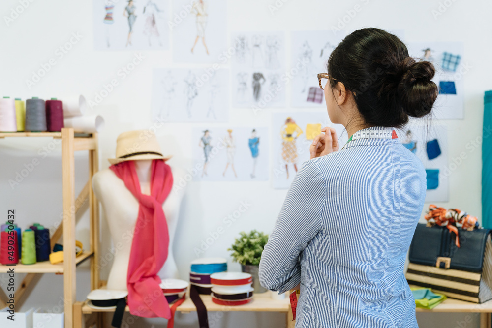Φωτογραφία Female fashion designer near paper sheet with drawings hanging on wall in modern office