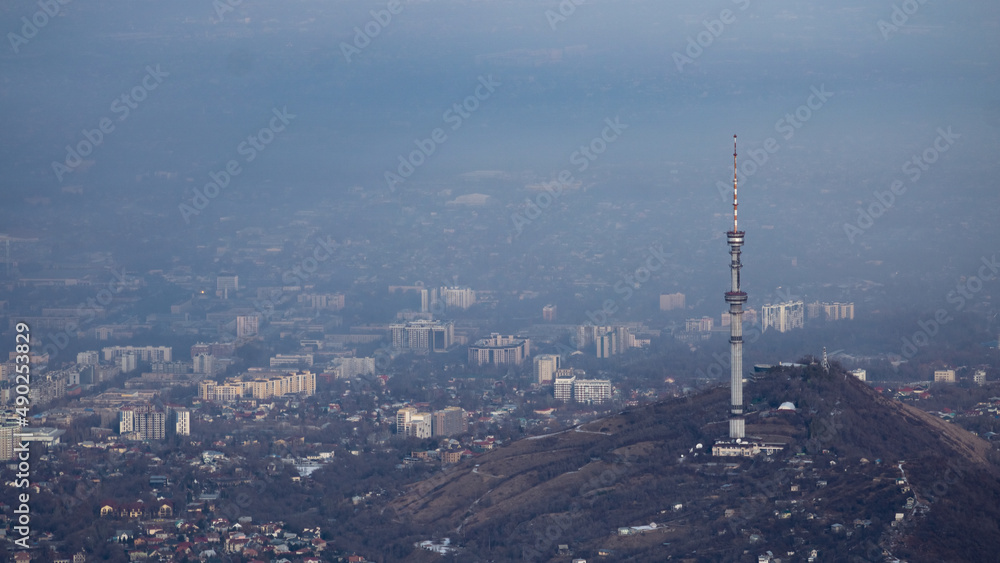 Naklejka premium A big city at the foot of the mountains under the clouds