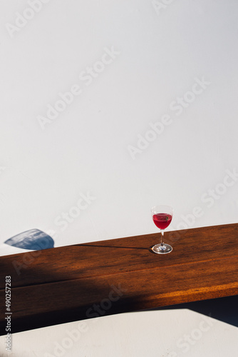 pink red magenta drink cocktail on wooden bench with white wall on boat, booze cruise. copy space. photo