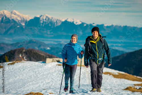 Young couple, male and female are hiking on a snow covered hill or mountain. Winter hike on Blegos, sunny hill in slovenian alps. photo