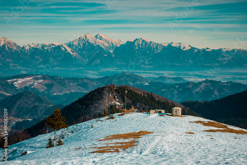 Young couple, male and female are hiking on a snow covered hill or mountain. Winter hike on Blegos, sunny hill in slovenian alps. photo