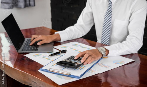 Fototapeta Naklejka Na Ścianę i Meble -  The businessman hand sits at their desks and calculates financial graphs showing the results of their investments planning the process of successful business growth