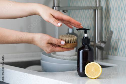 Fotografie A housewife clicks on a dispenser with an environmentally friendly dishwashing d