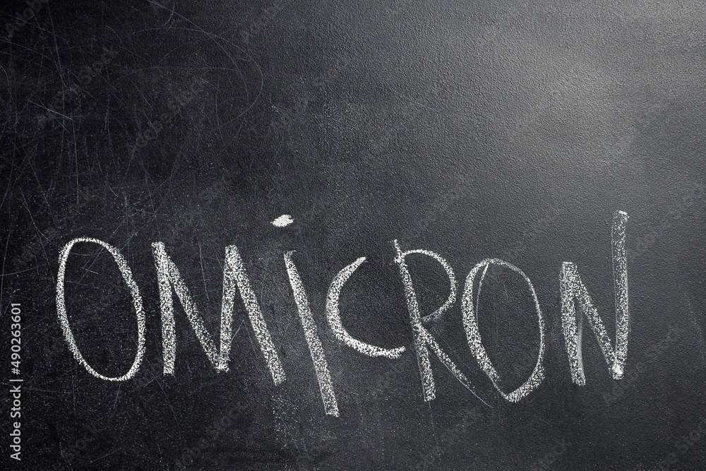 Obraz premium A close-up of the word Omicron written in white chalk on the black board. Omicron is one of the variants of Covid-19. Place to insert text.