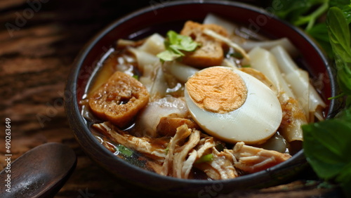Chinese roll noodle soup with chicken on wooden background
