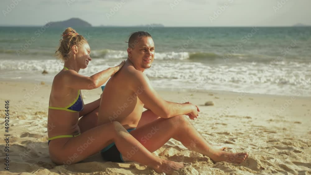 Carefree barefoot loving couple having sun block. Woman to put sunscreen man. Young girl and guy in hugging using sun cream. Concept rest tropical resort, traveling tourism happy summer holidays Carefree barefoot loving couple having sun block. Woman to put sunscreen man. Young girl and guy in hugging using sun cream. Concept rest tropical resort, traveling tourism happy summer holidays