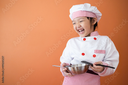 Little cute asian girl in chef costum. Concept for cooking learning for kid.