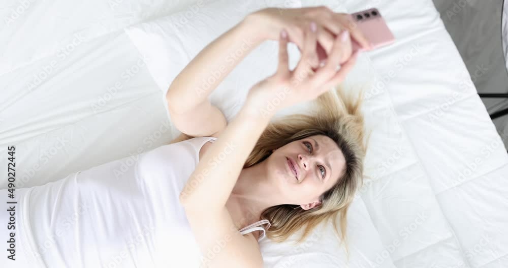 Woman takes selfie while lying on couch Woman takes selfie while lying on couch