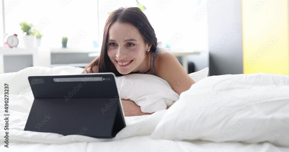 Smiling woman looking into tablet while lying on sofa Smiling woman looking into tablet while lying on sofa