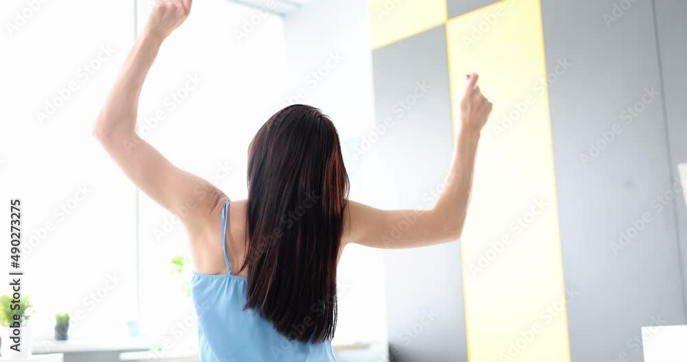 Young happy woman waking up in morning in white bed at home looking at window Young happy woman waking up in morning in white bed at home looking at window