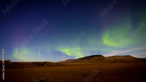 Aurora boreal con montañas de fondo en noche estrellada