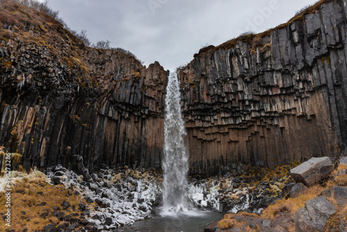 Cascada grande con nieve y columnas de basalto