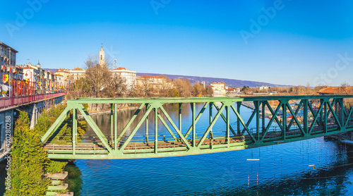View of an old iron railway bridge over the Dora Baltea river, in the city of Ivrea (Torino province,  Piedmont, Northern Italy)  world famous for its carnival, is UNESCO Site since 2018. © stefanopez