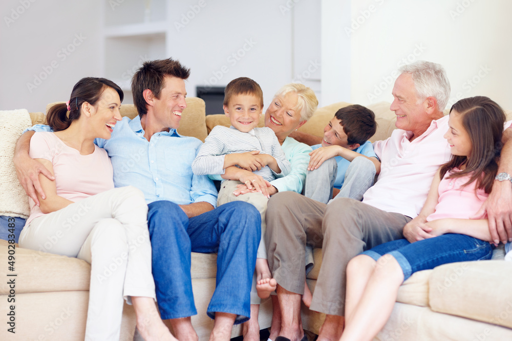 Three generations gather happily together. Three generations of family sitting together affectionately on the lounge couch. Three generations gather happily together. Three generations of family sitting together affectionately on the lounge couch.