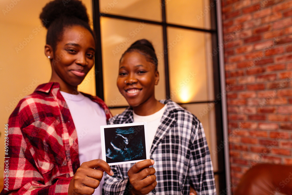 african american two happy future mothers sonogram image at home in evening african american two happy future mothers sonogram image at home in evening