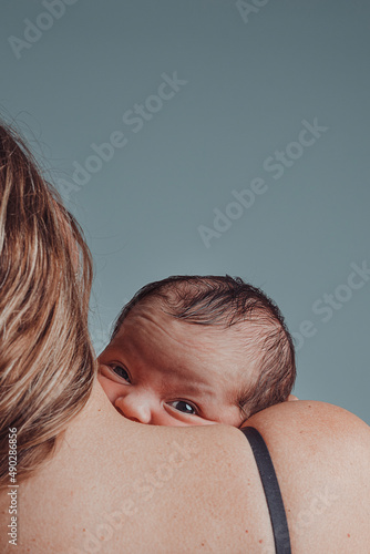 Foto Newborn in his mother's arms looks at camera with sympathetic expression