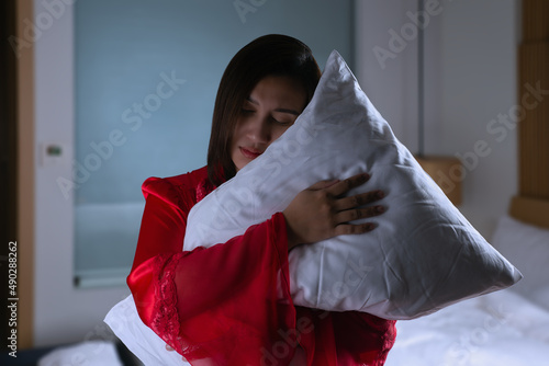 Foto Female in satin nightwear and embracing soft pillow