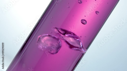 Glass test tube. Pink liquid in glass of  flask. Slow motion. Boiling and air bubbles in water. Cosmetics and perfumes. Extract from natural ingredients. Aromatherapy.