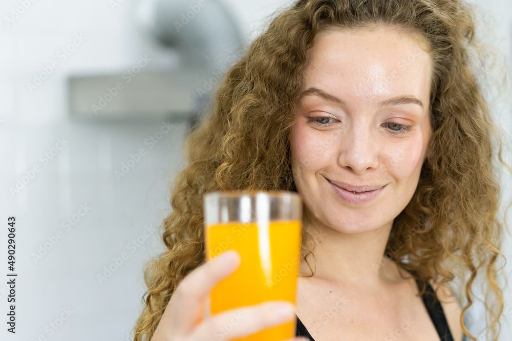 close up face of beautiful healthy woman look at orange juice in glass in kitchen with copy space. beautiful caucasian woman cooking healthy diet fruit or vegetable in kitchen close up face of beautiful healthy woman look at orange juice in glass in kitchen with copy space. beautiful caucasian woman cooking healthy diet fruit or vegetable in kitchen