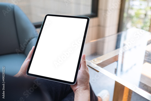 Mockup image of a woman holding digital tablet with blank white desktop screen in cafe photo