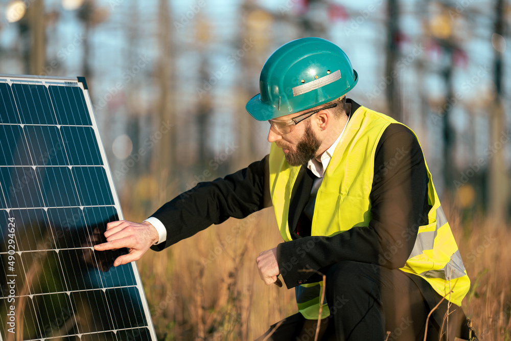 Electric engineer checking photovoltaic solar panels wearing helmet suit and safety vest Concept renewable energy, technology, electricity, service, green, future