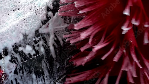 Black car moving though automatic car wash machine. The brush moving to clean the car. Slow motion shot